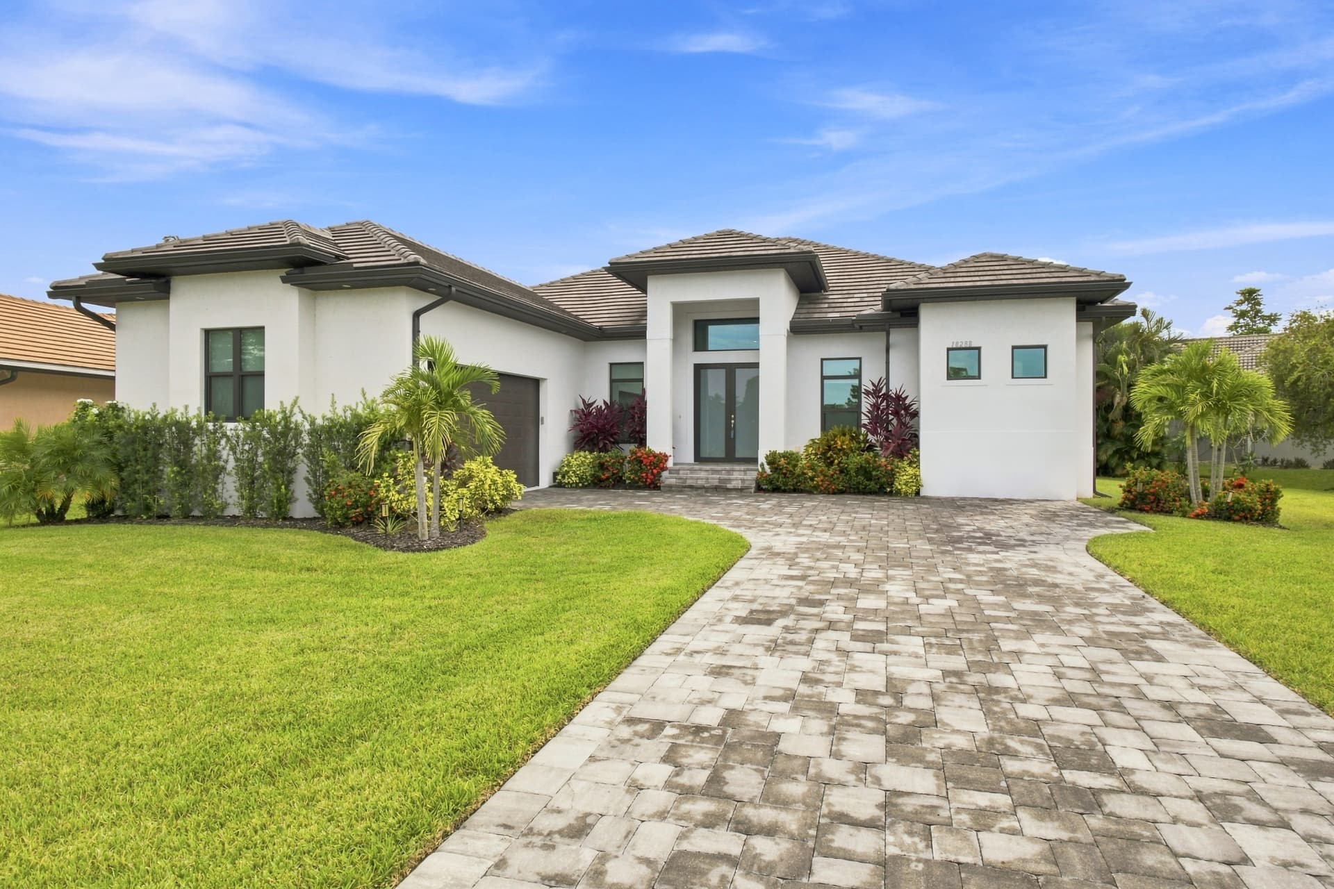 Front exterior of a Southwest Florida home with paver driveway and palm landscaping