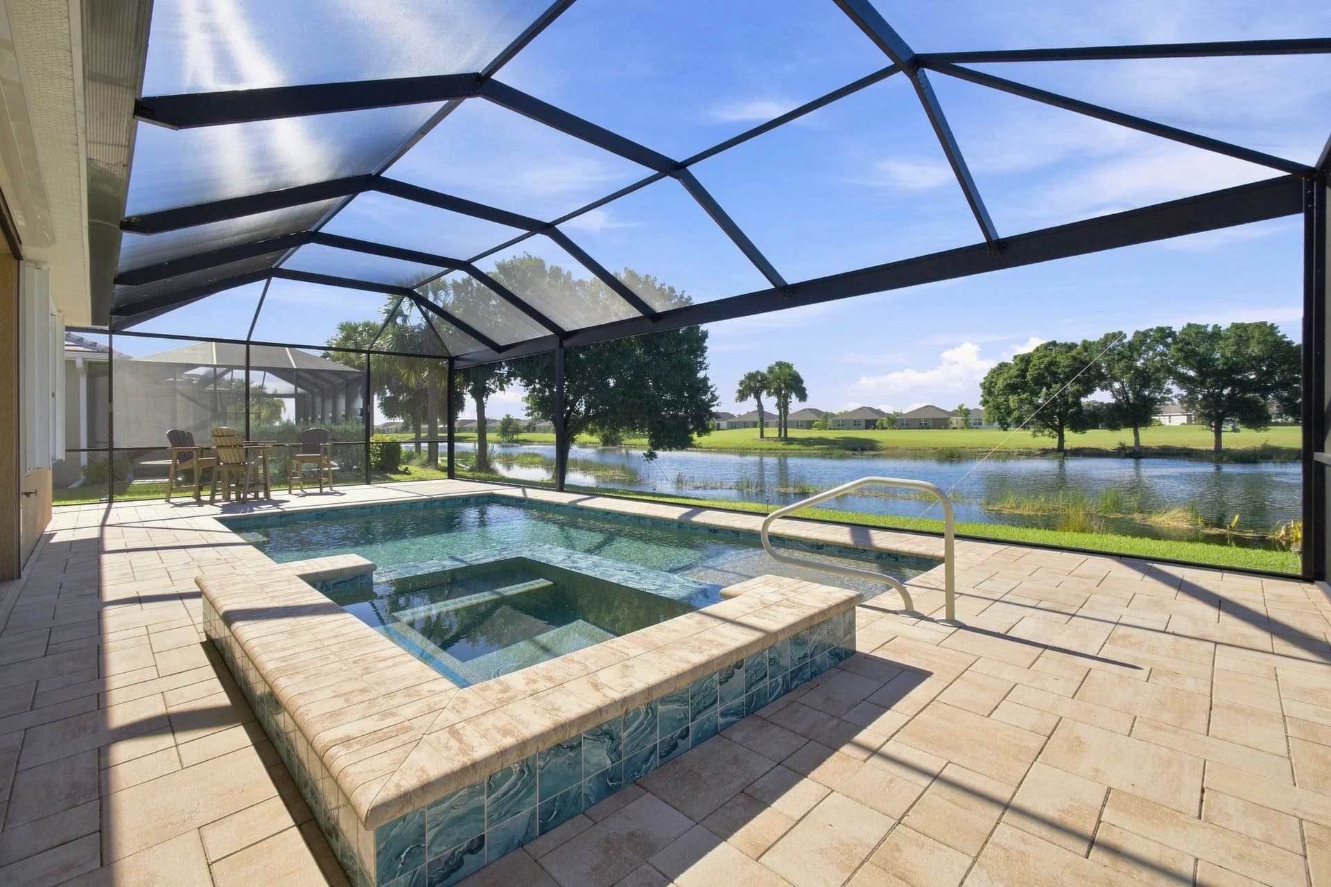 Screened pool and spa lanai with paver deck overlooking a lake in Southwest Florida