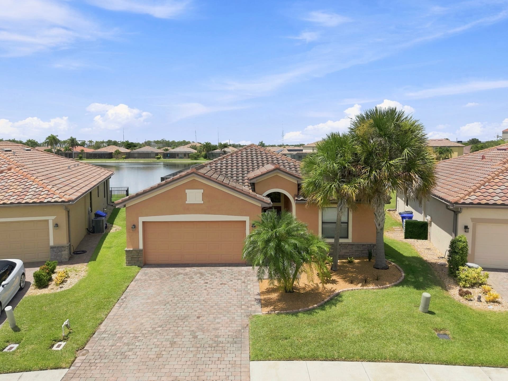 Drone photo of a Southwest Florida home with terracotta roof, paver driveway and neighborhood lake